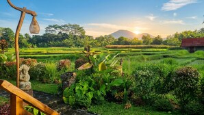 A serene landscape with terraced fields, a wooden structure, and a statue. - Sirya Farm House (Tabanan)