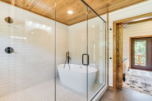 Une salle de bain moderne avec une baignoire sur pieds, une douche à parois de verre et un plafond en bois.