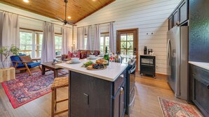 A spacious kitchen with a central island, wooden ceiling, and large windows. - Tree-Lined Broken Bow Studio Cabin w/ Hot Tub! (Broken Bow)