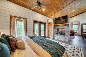 Une chambre spacieuse avec un grand lit, une cheminée en pierre et une vue sur l’extérieur.