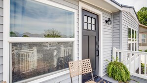 Ein Haus mit großem Fenster, einer Tür und einer Veranda mit Stuhl und Pflanzen.