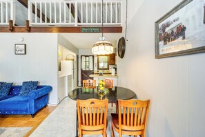 A dining area with a round table, wooden chairs, a blue sofa, and a chandelier. - Hike, Ski & Unwind: Woodsy Beech Mountain Retreat (Beech Mountain)
