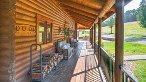 Een vakantiehuisje van hout met een overdekte veranda, houten trappen en een zithoek buiten.