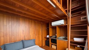 Een slaapkamer met een bed, houten wanden, een inbouwkast en een airconditioning.