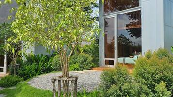 Un bâtiment moderne doté de grandes fenêtres en verre, un jardin bien entretenu avec différentes espèces de plantes et une structure en bois au premier plan.