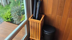 Een houten bank met parasols en een prullenbak tegen een houten muur.