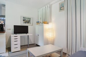 Une pièce comprenant un téléviseur posé sur un bureau, une armoire, une table et une lampe.