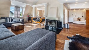 A spacious living room with a fireplace, a sofa set, and a leather rug.