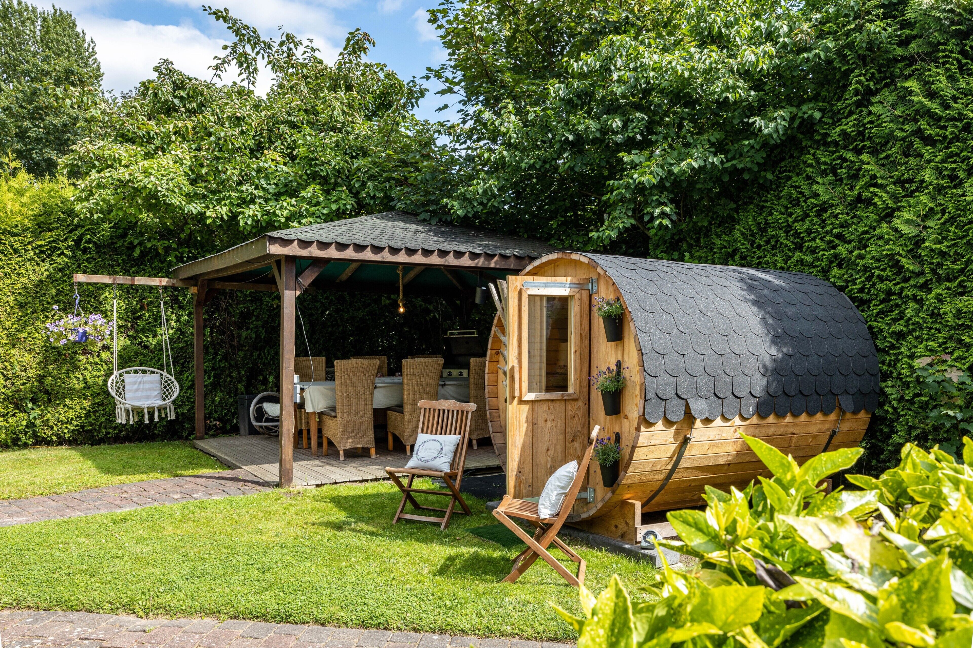 Eine Holzhütte mit gewölbtem Dach, einer Veranda mit Korbmöbeln und einem kleinen Garten.