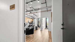 Ein modernes Interieur mit freiliegenden Lüftungsrohren, einer Küchenzeile und einer Sitzecke mit einem schwarzen Sessel.
