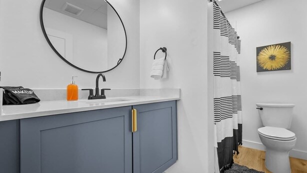 Ein Badezimmer mit einem weißen Waschbecken, einem Spiegel, einer Toilette und einer Duschvorhang.
