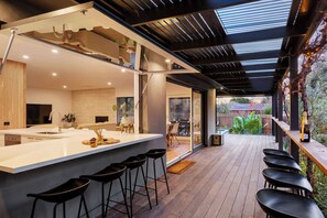 Una cocina moderna con una isla central, taburetes de bar y vista al patio trasero.