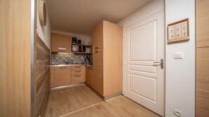A compact kitchen with wooden cabinets, a tiled backsplash, and a white door. - Lovely 4/6 pers Apt near the pistes (Allos)