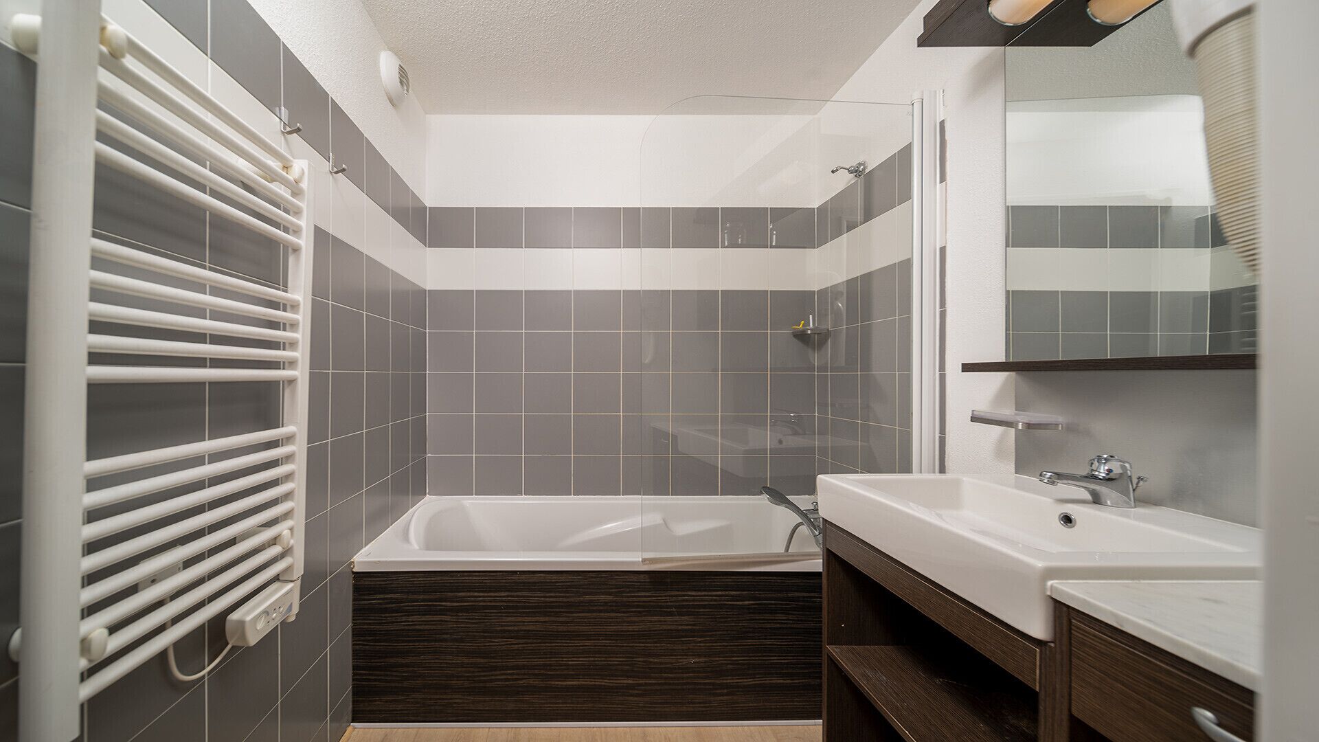 A modern bathroom with a bathtub, two sinks, a mirror, and a towel rack.