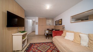 A compact living space with a sofa, a TV mounted on the wall, a dining area, and a kitchen area. - Lovely 4/6 pers Apt near the pistes (Allos)