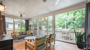 Un patio cubierto con terraza de madera, un sofá, una mesa de comedor y sillas.
