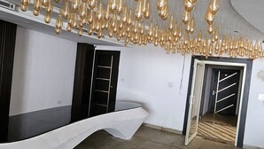 A spacious room with a modern, industrial design, featuring a unique ceiling with numerous hanging light fixtures and a curved white bench along one wall. - Jhansi Castle Inn (Jhansi)