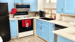 A kitchen with light blue cabinets, a black refrigerator, a microwave, a stove, and a sink. - Enchanting 2-bedroom house across ISU in Pocatello (Pocatello)