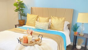A neatly made bed with a blue and white bedspread, gold pillows, and a tray of toiletries. - Enchanting 2-bedroom house across ISU in Pocatello (Pocatello)