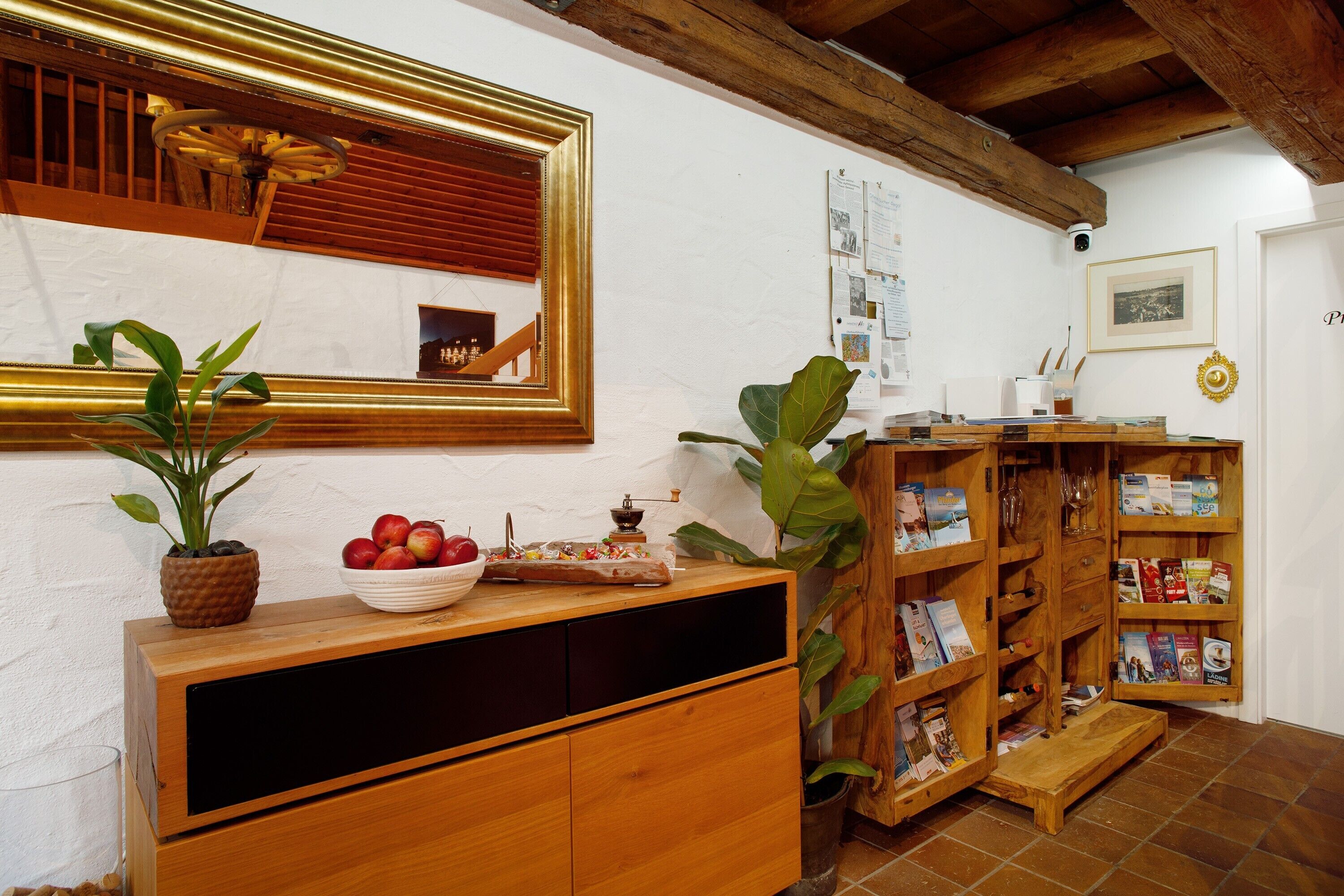 Een kamer met een houten kast, een spiegel, een boekenkast en een potplant.