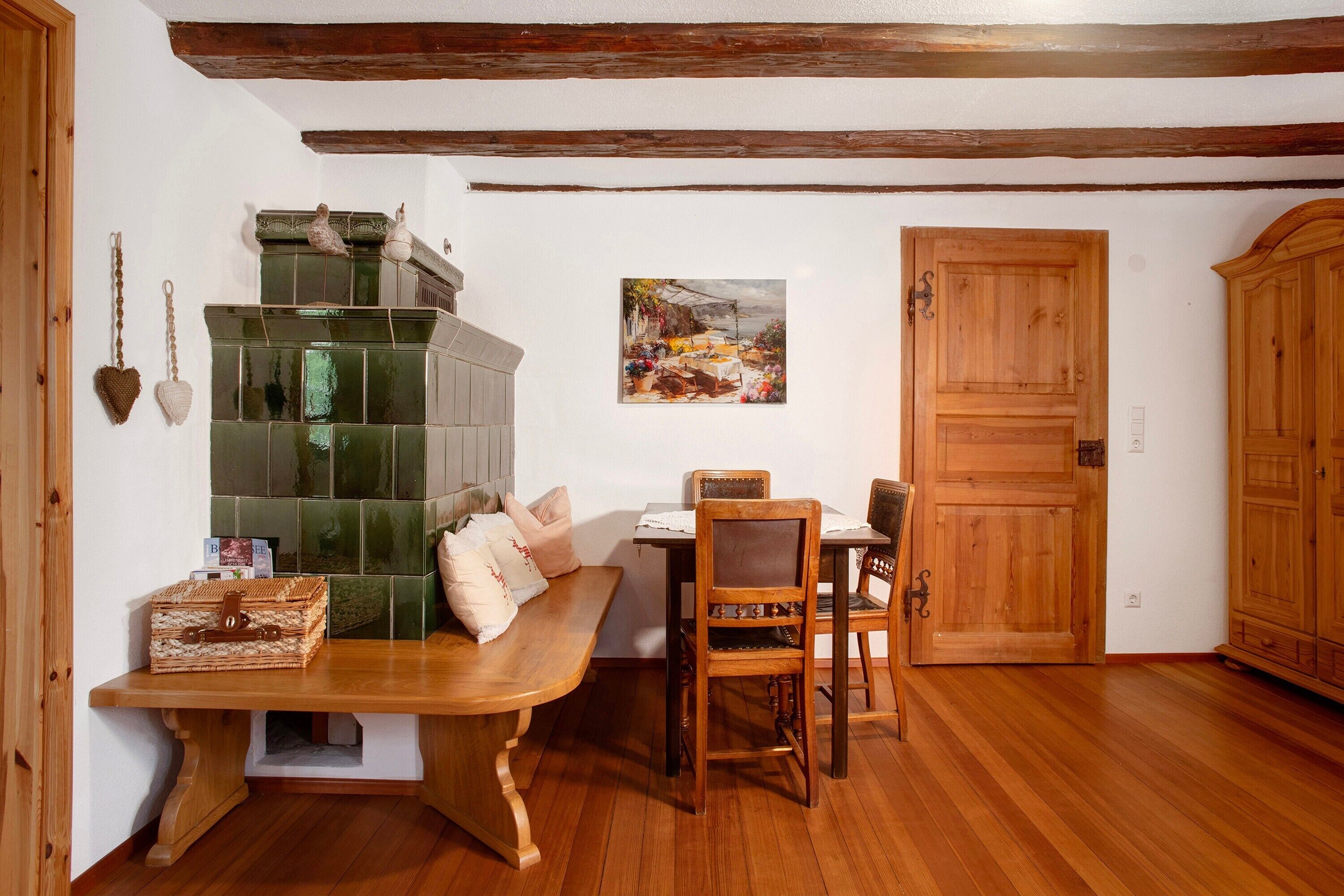 Un comedor con un banco de madera, sillas, una mesa, un salpicadero de azulejos verdes y una puerta de madera.