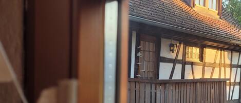 Una ventana con vista a un edificio tradicional con vigas de madera a la vista y un balcón.