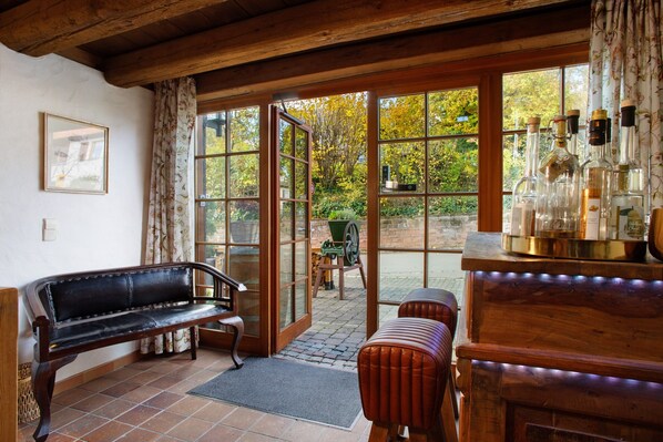 A room with a bench, a table with bottles, and a view through a glass door.