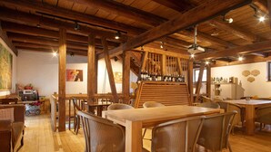 A rustic dining area with wooden beams, a long table, wicker chairs, and a wine rack. - Villa Puppenhaus – 'Apartment ehemalige Backstube' with Shared Terrace and Wi-Fi, Basement (Immenstaad am Bodensee)
