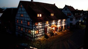 A traditional half-timbered house with a lit front entrance and a visible staircase leading to the door. - Villa Puppenhaus – 'Apartment ehemalige Backstube' with Shared Terrace and Wi-Fi, Basement (Immenstaad am Bodensee)