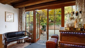 A room with a bench, a table with bottles, and a view through a glass door. - Villa Puppenhaus – Suite Bergblick with Sauna, Shared Terrace and Wi-Fi (Immenstaad am Bodensee)