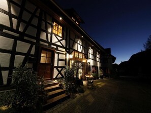 Ein traditionelles Fachwerkhäuschen mit gut beleuchtetem Eingang und einer Treppe, die hinauf führt.