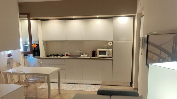 Un espace de vie compact comprenant un coin cuisine, un canapé, une table à manger et un téléviseur.