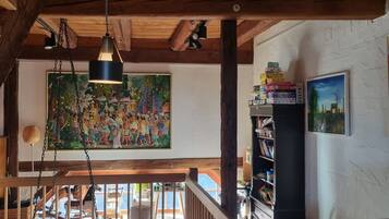 Ein Holzinnenraum mit hoher Decke, einem großen Gemälde und einem Bücherregal.
