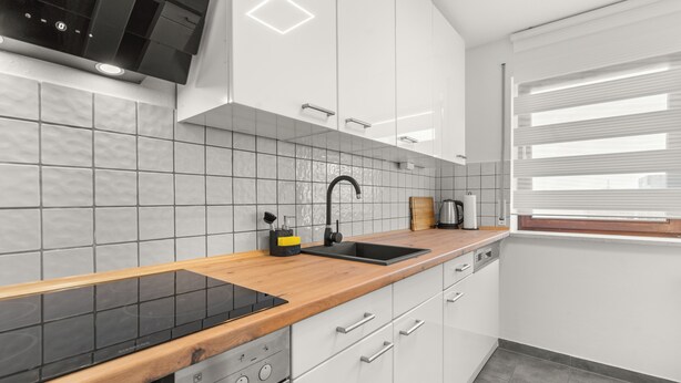 Eine moderne Küche mit weißen Schränken, einer schwarzen Arbeitsplatte und einem eingebauten Backofen.