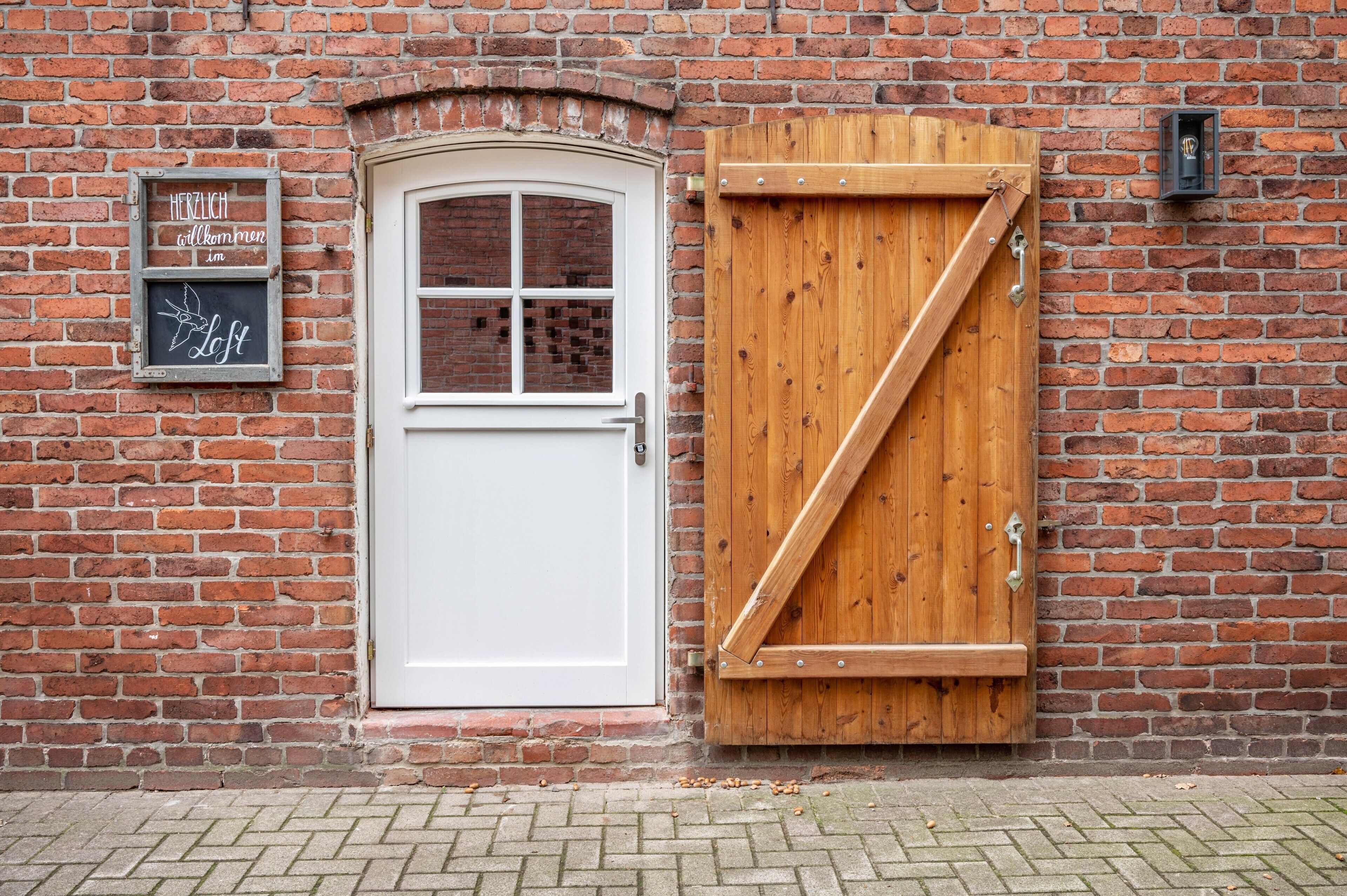 A brick wall with a white door and a wooden gate.