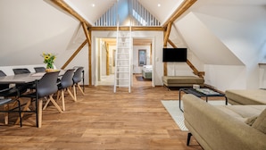 Une pièce de style loft comprenant un coin repas, un canapé et un téléviseur.
