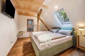 A bedroom with a sloped ceiling, a bed, a bedside table, a lamp, and a window. - Holiday Apartment "Eichengeflüster Schwalbenloft" with a Private Terrace under the Oaks (Wagenfeld)