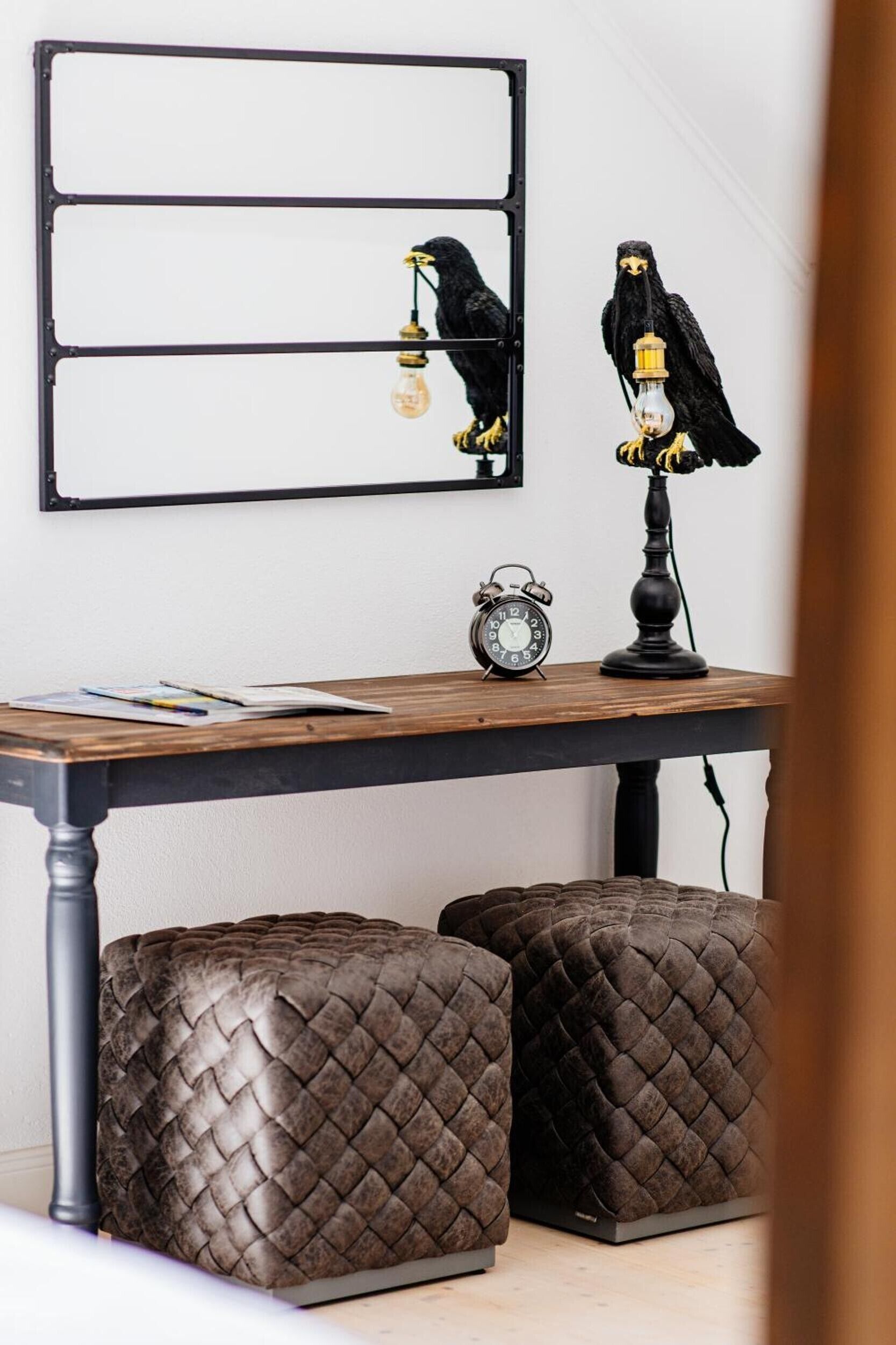 Ein Tisch mit einer Uhr, einer Lampe und zwei Vogeldekorationen.