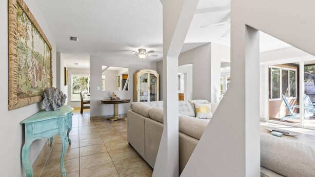 A spacious living area with a sofa, a coffee table, and a painting on the wall. - Coral Paradise Golf Course Pool Home | Close To The Beach | Palm Coast | Dog Friendly (Palm Coast)