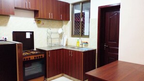 Una cocina con armarios de madera, una estufa a gas, un lavamanos y una ventana.