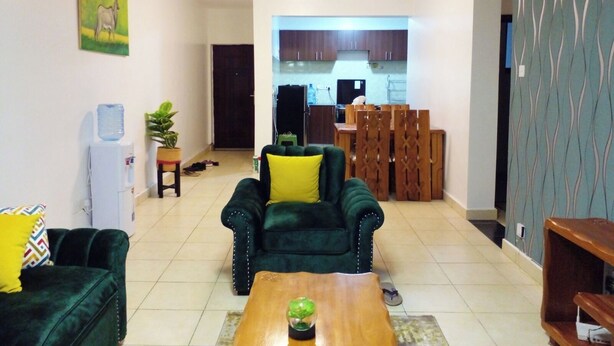 Una sala de estar con un sofá verde, una mesa de centro de madera y un comedor con sillas y una mesa de madera.