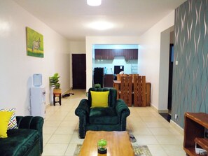 Una sala de estar con un sofá verde, una mesa de centro de madera y un comedor con sillas y una mesa de madera.