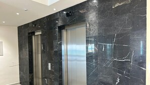 A modern elevator with a metallic finish, set in a hallway with black marble walls and light-colored tiles. - Depa Exclusivo, Hermosa Vista, CON UNA Extraordinaria Ubicación (Boca del Río)