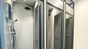 A modern bathroom with a glass-enclosed shower, a handheld showerhead, and a control panel. - U Capsule Hotel  (Kulai)