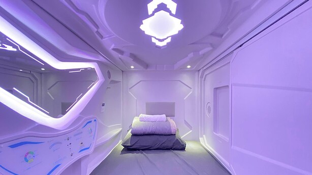 A futuristic bedroom with a bed, a control panel, and a unique ceiling design. - U Capsule Hotel  (Kulai)