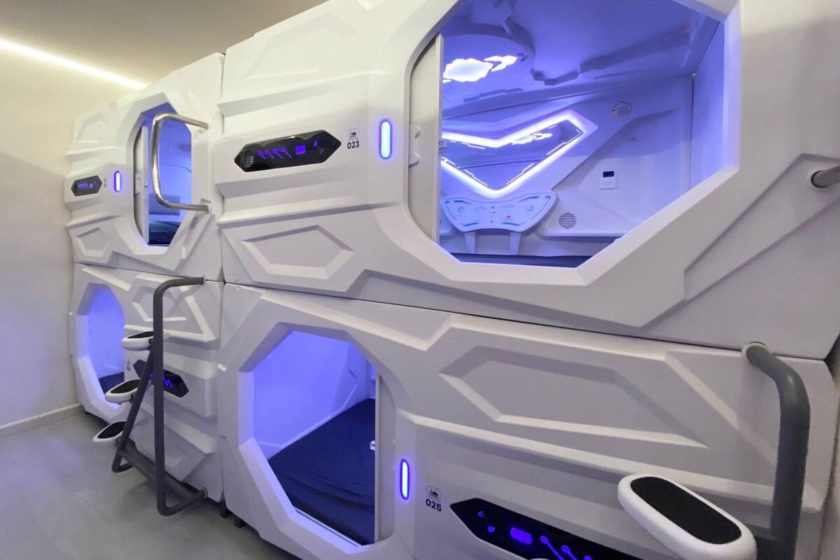 A row of hexagonal massage pods with illuminated interiors, each pod featuring a control panel and a small window.