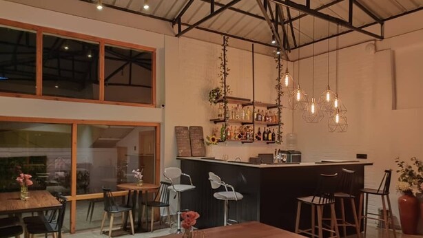 A modern kitchen with a bar area, wooden furniture, and hanging pendant lights. - Hotel Dralha  (Thimphu)