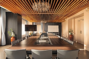 A conference room with a long table, chairs, a projector screen, and a large whiteboard. - Hotel Dralha  (Thimphu)