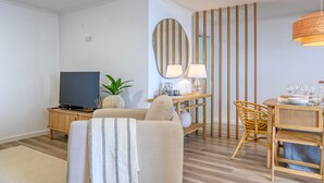 A modern living room with a sofa, TV, dining table, and chairs. - Vale dos Amores, a Home in Madeira (Calheta)