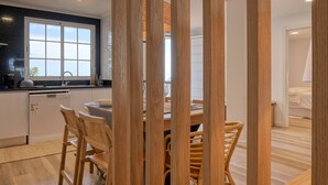 A modern kitchen with a large window, wooden chairs, and a dining table. - Vale dos Amores, a Home in Madeira (Calheta)